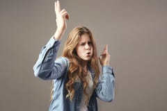 Славная девушка с длинными каштановыми волосами одетыми в белой футболке, джинсах и рубашке джинсов околпачивает вокруг на серой стоковое изображение rf Славная девушка с длинными каштановыми волосами одетыми в белой футболке, джинсах и рубашке джинсов околпачивает вокруг на серой стоковое изображение rf