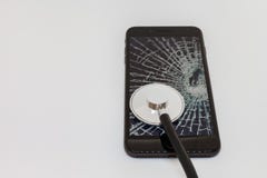 Стетоскоп полагается против экрана черного смартфона со сломленным стеклом стоковое фото Стетоскоп полагается против экрана черного смартфона со сломленным стеклом стоковое фото