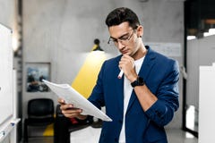 Стильный архитектор одетый в голубых checkered работах куртки и джинсов со светокопиями в современном офисе стоковое фото Стильный архитектор одетый в голубых checkered работах куртки и джинсов со светокопиями в современном офисе стоковое фото