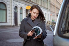 Счастливая женщина моды читая журнал на улице города стоковые фото Счастливая женщина моды читая журнал на улице города стоковые фото