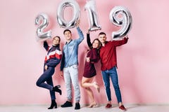 Счастливая компания 2 девушек и 2 парня одетого в стильных одеждах держат воздушные шары в форме 2019 стоковое фото Счастливая компания 2 девушек и 2 парня одетого в стильных одеждах держат воздушные шары в форме 2019 стоковое фото