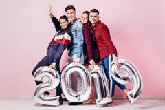 Счастливая компания 2 девушек и 2 парня одетого в стильных одеждах держат воздушные шары в форме 2019 дальше стоковое фото Счастливая компания 2 девушек и 2 парня одетого в стильных одеждах держат воздушные шары в форме 2019 дальше стоковое фото