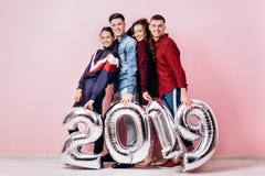 Счастливая компания 2 девушек и 2 парня одетого в стильных одеждах держат воздушные шары в форме 2019 дальше стоковое фото rf Счастливая компания 2 девушек и 2 парня одетого в стильных одеждах держат воздушные шары в форме 2019 дальше стоковое фото rf