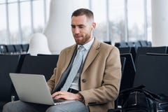 Счастливый бизнесмен работая на ноутбуке на гостиной аэропорта ждать Красивый кавказский бизнесмен на зале ожидания внутри стоковое изображение Счастливый бизнесмен работая на ноутбуке на гостиной аэропорта ждать Красивый кавказский бизнесмен на зале ожидания внутри стоковое изображение
