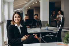 Усмехаясь бизнес-леди используя сотовый телефон с коллегами на предпосылке в офисе стоковые изображения Усмехаясь бизнес-леди используя сотовый телефон с коллегами на предпосылке в офисе стоковые изображения