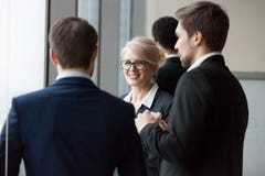 Усмехаясь коммерсантка наслаждаясь дружелюбным разговаривать с мужскими коллегами или партнерами стоковое изображение rf Усмехаясь коммерсантка наслаждаясь дружелюбным разговаривать с мужскими коллегами или партнерами стоковое изображение rf