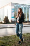Футболка девушки моды нося, джинсы и кожаная куртка представляя против улицы, городского стиля одежды стоковое изображение rf Футболка девушки моды нося, джинсы и кожаная куртка представляя против улицы, городского стиля одежды стоковое изображение rf