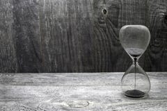 Часы с черными песчинками на деревянной винтажной предпосылке стоковое фото Часы с черными песчинками на деревянной винтажной предпосылке стоковое фото