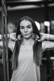 Черно-белое фото красивой атлетической девушки одетой в sporty одеждах стоя в спортзале с ее руками на ей стоковое фото rf Черно-белое фото красивой атлетической девушки одетой в sporty одеждах стоя в спортзале с ее руками на ей стоковое фото rf