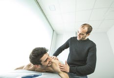 Хиропрактор массажируя плечо молодого человека Концепция физиотерапии стоковое изображение Хиропрактор массажируя плечо молодого человека Концепция физиотерапии стоковое изображение