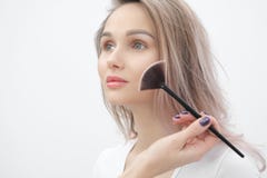 Художник макияжа делает макияжем красивую белокурую девушку на белой предпосылке Руки конца-вверх с щеткой и стороной стоковое фото Художник макияжа делает макияжем красивую белокурую девушку на белой предпосылке Руки конца-вверх с щеткой и стороной стоковое фото