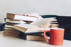 Рука человека принимает книгу на таблице кроватью Много книг и кофе кофе на прикроватном столике стоковые изображения rf Рука человека принимает книгу на таблице кроватью Много книг и кофе кофе на прикроватном столике стоковые изображения rf