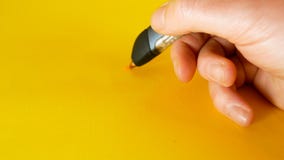 Рука человека рисует с ручкой на желтой предпосылке, идеалом принтера 3d отснятого видеоматериала для тем как нововведение, техно стоковая фотография Рука человека рисует с ручкой на желтой предпосылке, идеалом принтера 3d отснятого видеоматериала для тем как нововведение, техно стоковая фотография