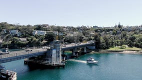 Órbita aérea de un puente con el barco que pasa debajo de tráfico Puente del escupitajo almacen de metraje de vídeo Órbita aérea de un puente con el barco que pasa debajo de tráfico Puente del escupitajo almacen de metraje de vídeo