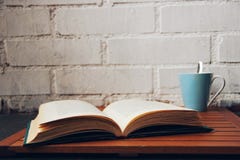 Öppen bok bredvid en kaffekopp arkivfoto Öppen bok bredvid en kaffekopp arkivfoto