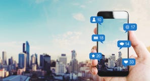 Übergeben Sie das Halten des intelligenten Mobiltelefons, mit Mitteilungsikonen und Stadthintergrund lizenzfreie stockbilder Übergeben Sie das Halten des intelligenten Mobiltelefons, mit Mitteilungsikonen und Stadthintergrund lizenzfreie stockbilder