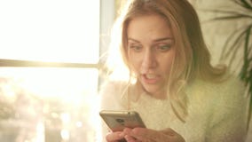 Überraschte Frauenlesemitteilung am Telefon Nettes Mädchen mit überraschtem Gesicht stock footage Überraschte Frauenlesemitteilung am Telefon Nettes Mädchen mit überraschtem Gesicht stock footage