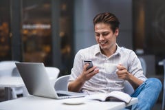 Überzeugter junger Mann in der intelligenten Freizeitkleidung, die eine Schale hält und durch Smartphone spricht stockbilder Überzeugter junger Mann in der intelligenten Freizeitkleidung, die eine Schale hält und durch Smartphone spricht stockbilder