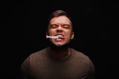 Ćpun z narkomaniami zaciska między zębami strzykawkę z injectable lekiem na ciemnego czerni tle zdjęcia royalty free Ćpun z narkomaniami zaciska między zębami strzykawkę z injectable lekiem na ciemnego czerni tle zdjęcia royalty free