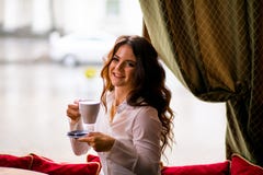 Ładna brunetki kobieta z długie włosy pije kawą w ono uśmiecha się i kawiarni zdjęcia stock Ładna brunetki kobieta z długie włosy pije kawą w ono uśmiecha się i kawiarni zdjęcia stock
