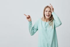 Ładna dziewczyna z blondynki mienia długie włosy ręką na głowie wskazuje palec wskazującego, jakby zapominał coś znacząco obrazy stock Ładna dziewczyna z blondynki mienia długie włosy ręką na głowie wskazuje palec wskazującego, jakby zapominał coś znacząco obrazy stock