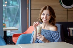 Ładny młodej kobiety obsiadanie w kawiarni z filiżanki kawy latte fotografia stock Ładny młodej kobiety obsiadanie w kawiarni z filiżanki kawy latte fotografia stock