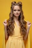 Śliczna młoda dziewczyna w żółtej sukni na żółtym tle z kędzierzawy długie włosy i ostrzyżeniem zdjęcie royalty free Śliczna młoda dziewczyna w żółtej sukni na żółtym tle z kędzierzawy długie włosy i ostrzyżeniem zdjęcie royalty free