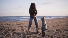 Śmieszna matka i mały dziecko w ciepłych ubraniach tanczymy, skaczemy i mamy, zabawę na piasek plaży nadmorski z oceanem lub morz zbiory wideo Śmieszna matka i mały dziecko w ciepłych ubraniach tanczymy, skaczemy i mamy, zabawę na piasek plaży nadmorski z oceanem lub morz zbiory wideo