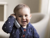 Średni horyzontalny strzał uczciwa uśmiechnięta berbeć dziewczyna trzyma zabawkarskiego telefon paserski jej ucho obrazy royalty free Średni horyzontalny strzał uczciwa uśmiechnięta berbeć dziewczyna trzyma zabawkarskiego telefon paserski jej ucho obrazy royalty free