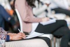 Żeńska ręka pisze puszek notatkach przy konferencją zdjęcia stock Żeńska ręka pisze puszek notatkach przy konferencją zdjęcia stock