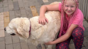 Życie z zwierzętami domowymi w nowożytnym mieście - dziewczyna muska jej psa na ulicie z niekonwencjonalnym pojawieniem zbiory wideo Życie z zwierzętami domowymi w nowożytnym mieście - dziewczyna muska jej psa na ulicie z niekonwencjonalnym pojawieniem zbiory wideo