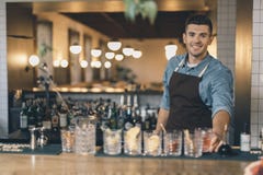 Życzliwy młody barista przed koktajlami na baru kontuarze obraz stock Życzliwy młody barista przed koktajlami na baru kontuarze obraz stock