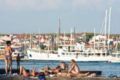 Άνθρωποι στα μαγιό που κάνουν ηλιοθεραπεία στην αποβάθρα στην παραλία στοκ εικόνα με δικαίωμα ελεύθερης χρήσης Άνθρωποι στα μαγιό που κάνουν ηλιοθεραπεία στην αποβάθρα στην παραλία στοκ εικόνα με δικαίωμα ελεύθερης χρήσης