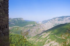 Άποψη του πράσινου μπλε ουρανού βουνών, άκρη ενός τοίχου πετρών Μοναστήρι Tatev, περιοχή Syunik, της Αρμενίας στοκ εικόνα Άποψη του πράσινου μπλε ουρανού βουνών, άκρη ενός τοίχου πετρών Μοναστήρι Tatev, περιοχή Syunik, της Αρμενίας στοκ εικόνα