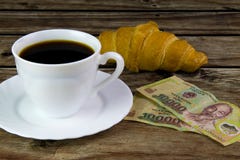 Άσπρο φλυτζάνι του μαύρου καφέ, των croissant και βιετναμέζικων χρημάτων στοκ εικόνες Άσπρο φλυτζάνι του μαύρου καφέ, των croissant και βιετναμέζικων χρημάτων στοκ εικόνες