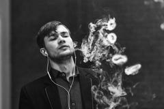 Άτομο Vape Ο νέος όμορφος άσπρος τύπος άφησε τα δαχτυλίδια από τον ατμό από το ηλεκτρονικό τσιγάρο Γραπτή φωτογραφία του Πεκίνου, Στοκ εικόνες με δικαίωμα ελεύθερης χρήσης Άτομο Vape Ο νέος όμορφος άσπρος τύπος άφησε τα δαχτυλίδια από τον ατμό από το ηλεκτρονικό τσιγάρο Γραπτή φωτογραφία του Πεκίνου, Στοκ εικόνες με δικαίωμα ελεύθερης χρήσης