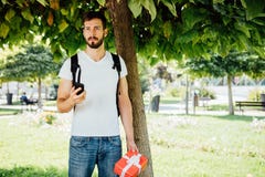 Άτομο με το σακίδιο πλάτης και ένα δώρο δίπλα σε ένα δέντρο στοκ εικόνες με δικαίωμα ελεύθερης χρήσης Άτομο με το σακίδιο πλάτης και ένα δώρο δίπλα σε ένα δέντρο στοκ εικόνες με δικαίωμα ελεύθερης χρήσης