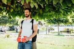 Άτομο με το σακίδιο πλάτης και ένα δώρο δίπλα σε ένα δέντρο στοκ εικόνες με δικαίωμα ελεύθερης χρήσης Άτομο με το σακίδιο πλάτης και ένα δώρο δίπλα σε ένα δέντρο στοκ εικόνες με δικαίωμα ελεύθερης χρήσης
