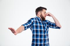 Άτομο που καλύπτει τη μύτη του και που παρουσιάζει χειρονομία στάσεων με το φοίνικα Στοκ Εικόνες Άτομο που καλύπτει τη μύτη του και που παρουσιάζει χειρονομία στάσεων με το φοίνικα Στοκ Εικόνες