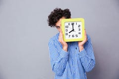 Άτομο που καλύπτει το πρόσωπο με το ρολόι και που εξετάζει τη κάμερα Στοκ φωτογραφίες με δικαίωμα ελεύθερης χρήσης Άτομο που καλύπτει το πρόσωπο με το ρολόι και που εξετάζει τη κάμερα Στοκ φωτογραφίες με δικαίωμα ελεύθερης χρήσης