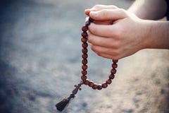 Άτομο που κρατά ξύλινες rosary και μια επίκληση στοκ φωτογραφία Άτομο που κρατά ξύλινες rosary και μια επίκληση στοκ φωτογραφία