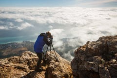 Άτομο που στέκεται με ένα τρίποδο και μια κάμερα σε μια αιχμή υψηλών βουνών επάνω από τα σύννεφα, την πόλη και τη θάλασσα Επαγγελ Στοκ Φωτογραφίες Άτομο που στέκεται με ένα τρίποδο και μια κάμερα σε μια αιχμή υψηλών βουνών επάνω από τα σύννεφα, την πόλη και τη θάλασσα Επαγγελ Στοκ Φωτογραφίες