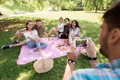 Άτομο που φωτογραφίζει τους φίλους από το smartphone στο πικ-νίκ Στοκ εικόνα με δικαίωμα ελεύθερης χρήσης Άτομο που φωτογραφίζει τους φίλους από το smartphone στο πικ-νίκ Στοκ εικόνα με δικαίωμα ελεύθερης χρήσης