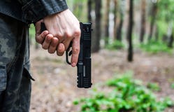 Άτομο στα στρατιωτικά ενδύματα που κρατά ένα πυροβόλο όπλο κάτω στοκ φωτογραφίες Άτομο στα στρατιωτικά ενδύματα που κρατά ένα πυροβόλο όπλο κάτω στοκ φωτογραφίες