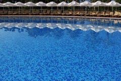 Έδρες και πισίνα ομπρελών πλησίον Στοκ φωτογραφία με δικαίωμα ελεύθερης χρήσης Έδρες και πισίνα ομπρελών πλησίον Στοκ φωτογραφία με δικαίωμα ελεύθερης χρήσης