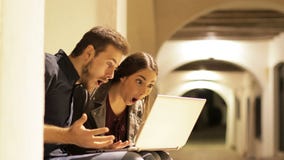Έκπληκτο ζεύγος που βρίσκει το περιεχόμενο στο lap-top στη νύχτα απόθεμα βίντεο Έκπληκτο ζεύγος που βρίσκει το περιεχόμενο στο lap-top στη νύχτα απόθεμα βίντεο