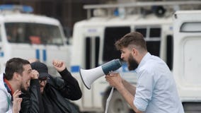 Ένα άτομο με μια γενειάδα φωνάζει δυνατά στους ανθρώπους megaphone απόθεμα βίντεο Ένα άτομο με μια γενειάδα φωνάζει δυνατά στους ανθρώπους megaphone απόθεμα βίντεο