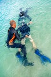 Ένα άτομο σε ένα κοστούμι για την κατάδυση προετοιμάζει ένα αγόρι για να βουτήξει στοκ εικόνες Ένα άτομο σε ένα κοστούμι για την κατάδυση προετοιμάζει ένα αγόρι για να βουτήξει στοκ εικόνες