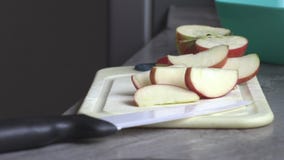 Ένα άτομο στην κουζίνα που τεμαχίζει ένα μήλο Ένα άτομο στην κουζίνα που τεμαχίζει ένα μήλο