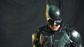 Ένα άτομο στις στάσεις Batman κοστουμιών σε ένα δωμάτιο που καλύπτεται με ένα σκοτεινό ύφασμα, αυξάνει το κεφάλι του και εξετάζει Ένα άτομο στις στάσεις Batman κοστουμιών σε ένα δωμάτιο που καλύπτεται με ένα σκοτεινό ύφασμα, αυξάνει το κεφάλι του και εξετάζει